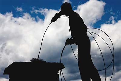 Silhouette of chimney sweep performing chimney service in Monmouth County