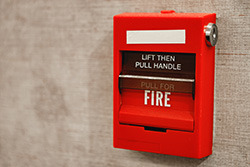 Red fire alarm box on a tan wall